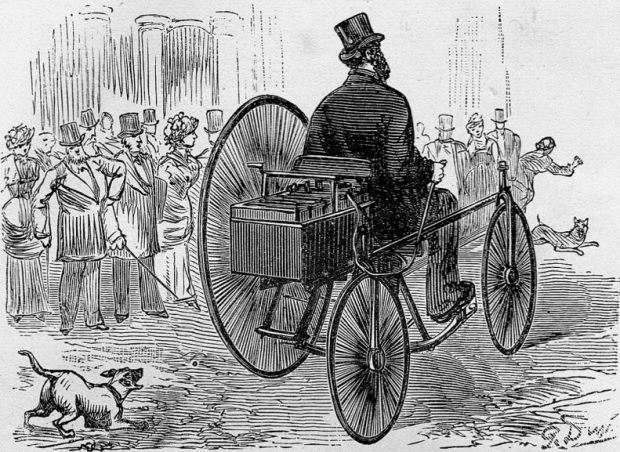 Woodcut of a shocked crowd watching a man in a coat and top hat drive a three-wheeled electric vehicle along a cobbled street, chased by several barking dogs.