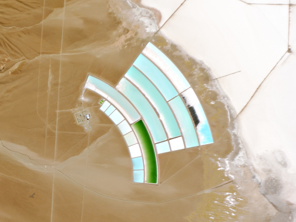 Satellite photograph of a salt flats, which has been cut into massive arc-shaped ponds.