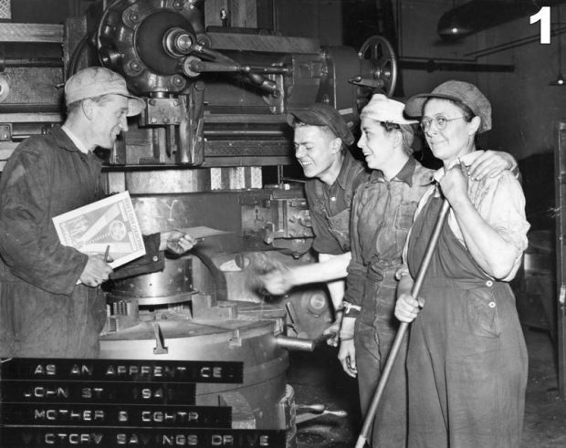 Black and white archival photograph of two men and two women stand in front of a large machine. The woman in the foreground is looking at the camera and holding a broom handle. The men and woman in the background are laughing and one is handing a piece of paper to the other. There is faded printing at the bottom left corner which reads “AS AN APPRENTICE/JOHN STREET 1941/MOTHER & DAUGHTER/VICTORY SAVINGS DRIVE”.