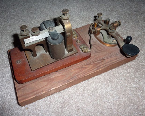 Colour photograph of a telegraph key and sounder mounted on a wooden platform.