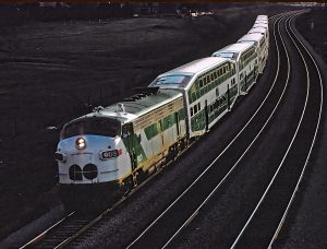 Photographie en couleur d’une locomotive GO Transit et de sept wagons roulant sur une voie ferrée. Il y a deux voies vides à côté du train.