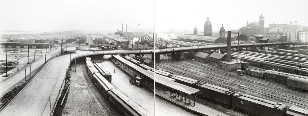 Black and white cityscape vintage photograph showing a large bridge over railway tracks.