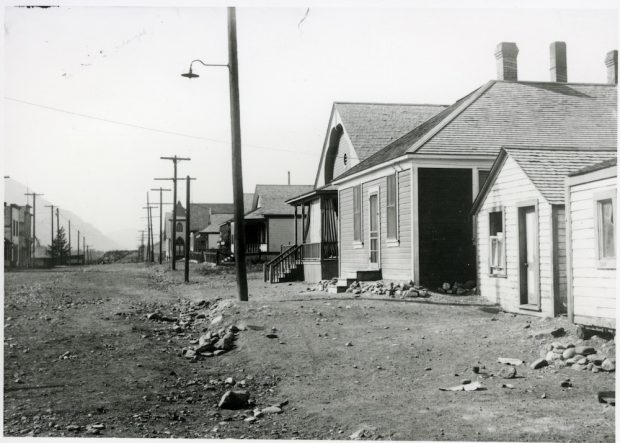 Street with a row of houses on the right side; the Alberta Provincial Police barracks is in the middle.