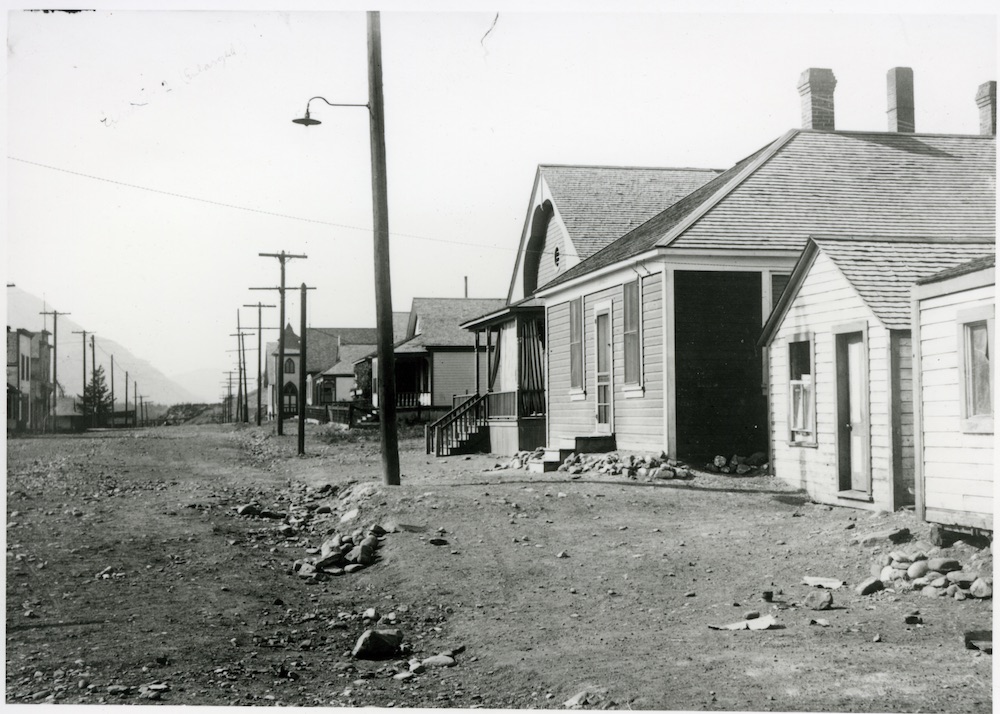 Rue avec une rangée de maisons sur le côté droit; la caserne de la police provinciale de l'Alberta est au milieu.