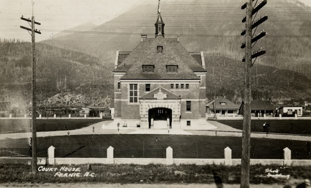 The Fernie Courthouse building surrounded by lawns and an iron fence.