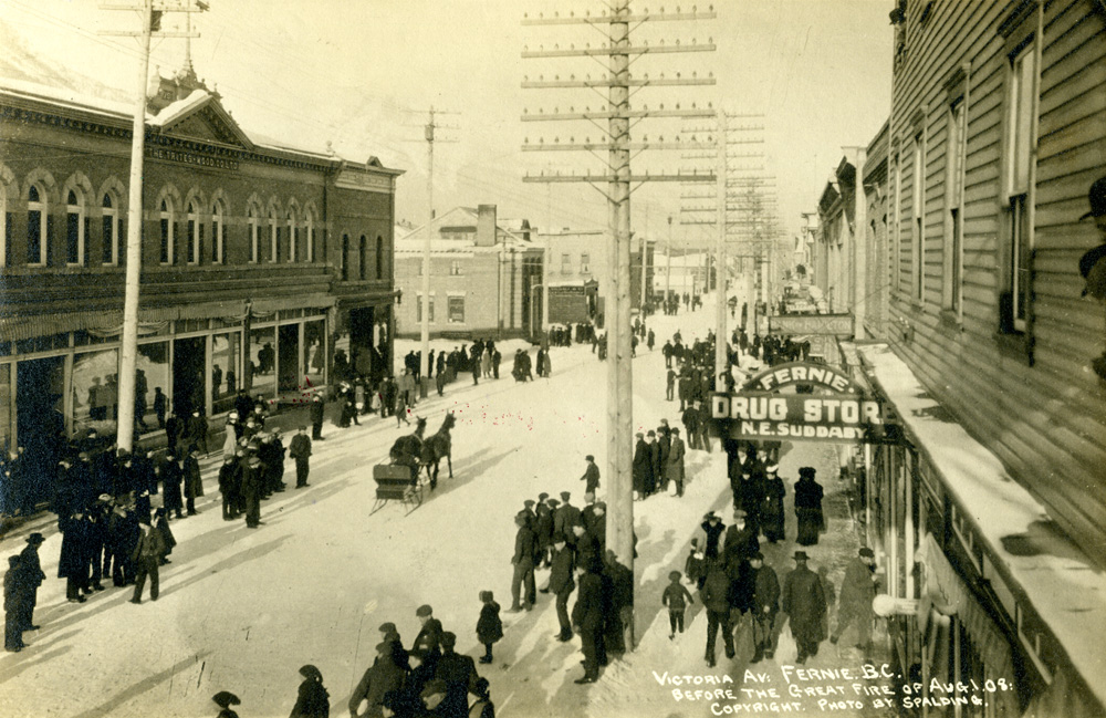 Downtown Fernie (2nd Avenue) in winter, with shops, men and women on the street, and a sleigh pulled by two horses.