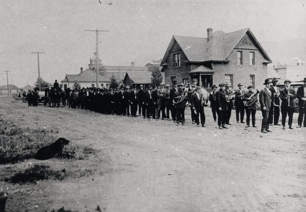 Parade procession of men marching two-by-two.