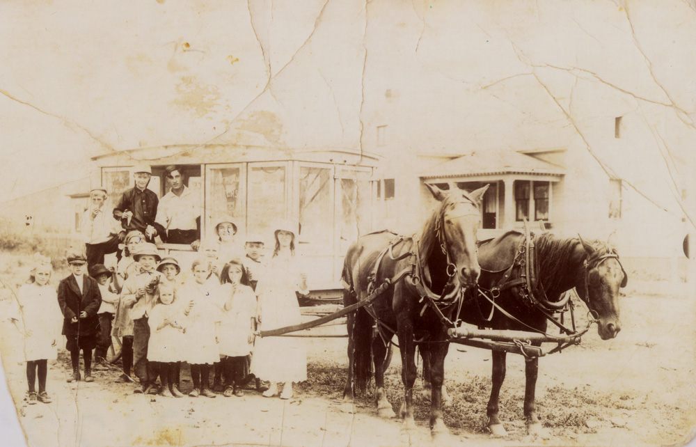 Ice cream wagon pulled by two horses with children in front.