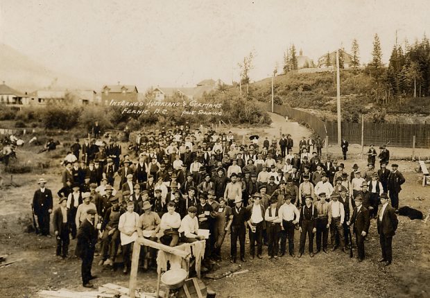 Large roup of men standing in a camp yard.