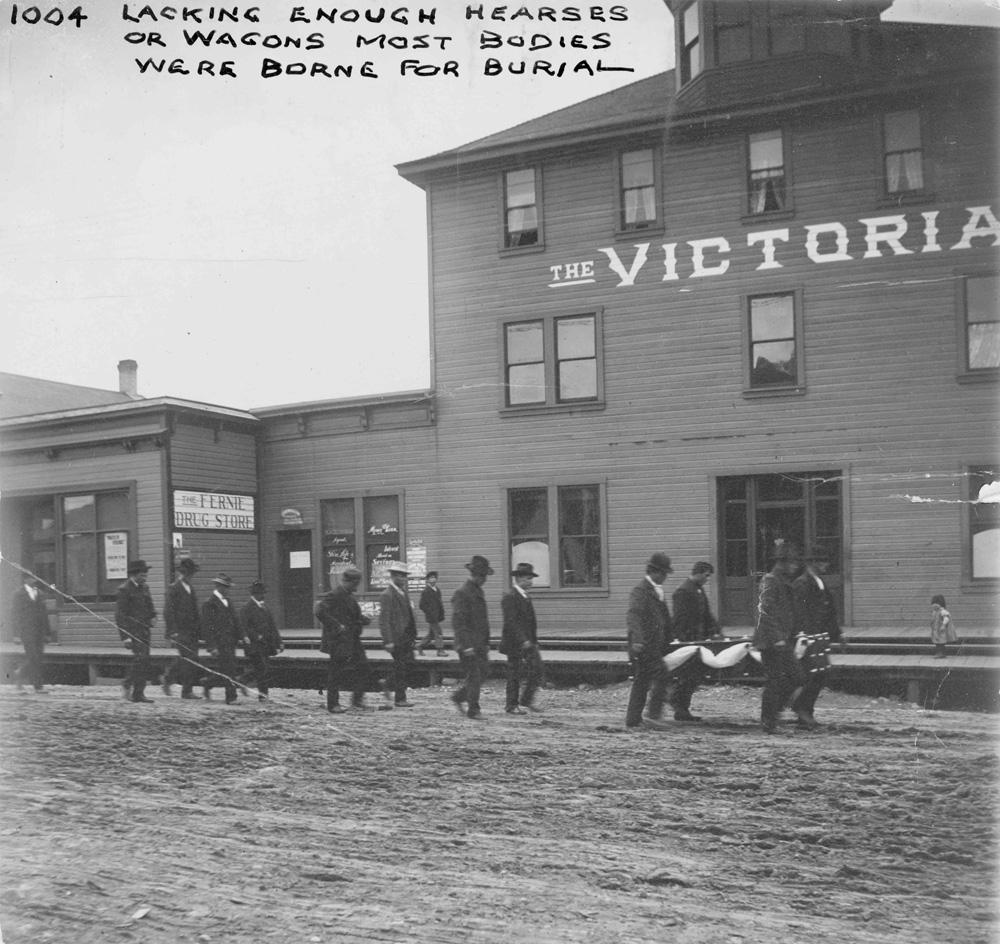 Funeral procession. Men carrying a stretcher with men following.