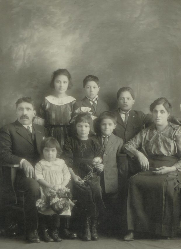 A family with dad sitting on the left, mom sitting on the right and six children standing between them.
