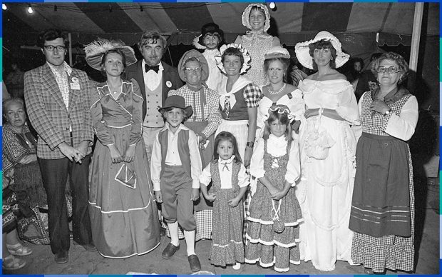 A black and white photograph of a group of adults and children dressed in historical costumes.