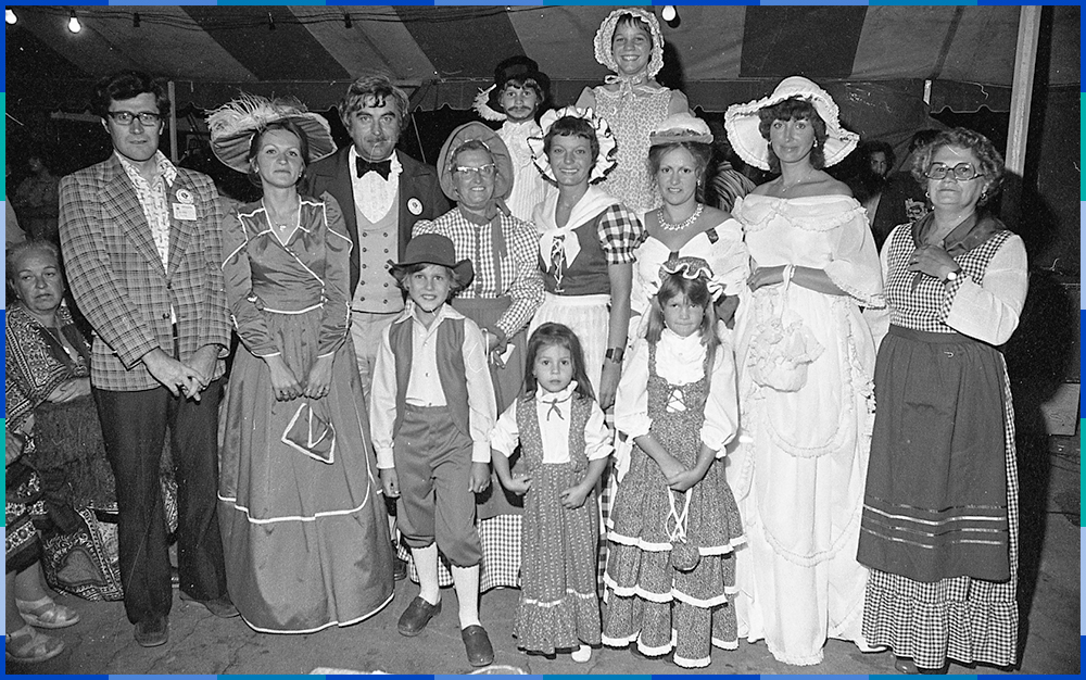 A black and white photograph of a group of adults and children dressed in historical costumes.