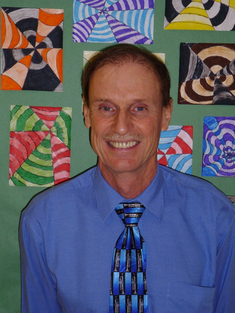 Man in a shirt and tie smiles at camera.