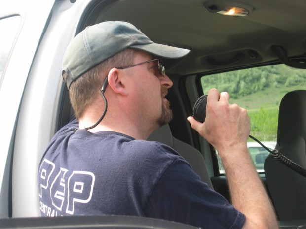 Man with his back turned speaking into a radio.