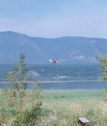 Aeroplane flying over the lake. Hills in the background.