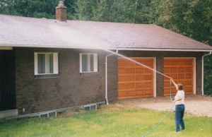 Woman sprays water on to the roof of her house.