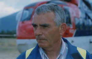 Portrait of a serious looking man wearing coveralls. Helicopter in background.