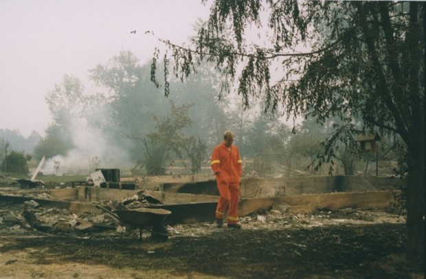 Fireman walks through burning embers. A building's foundation is all that is left after the fire.