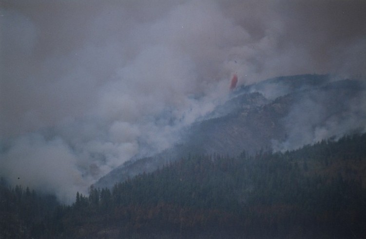 Fire in hills. Red fire retardant being dropped from a helicopter.