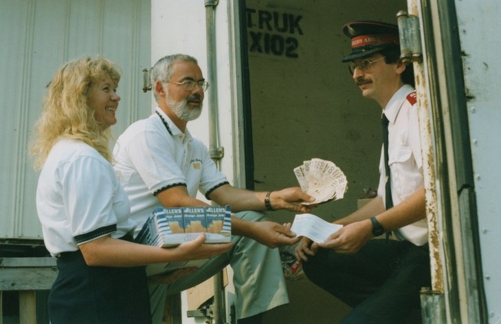 Man and woman present several hundred dollar bills, a cheque and juice boxes to Salvation Army officer.