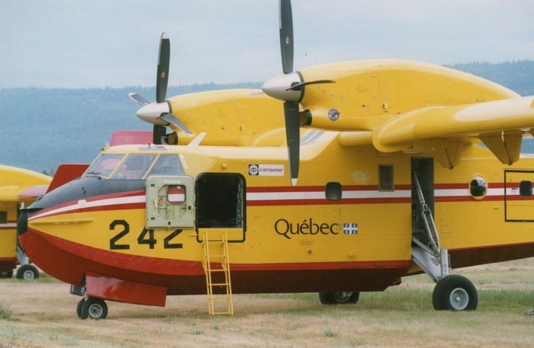 Yellow plane with red and white stripe, dual propellers, Numbered 242 and Quebec on its belly.