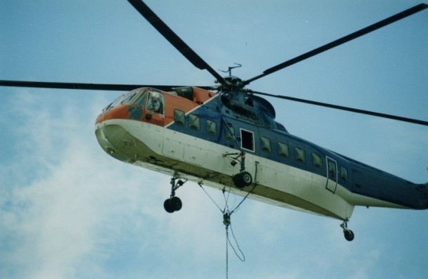 A helicopter in flight. Cable suspended from it.