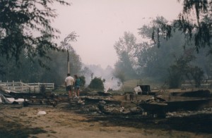 Couple walks away from camera. Burned rubble and a foundation in foreground.