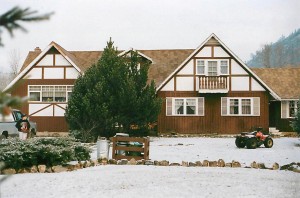 House with Tudor influences, three gables, 1.5 storey, young adult walks in front.