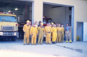 Quatorze pompiers rassemblés en avant d'une caserne de pompiers.