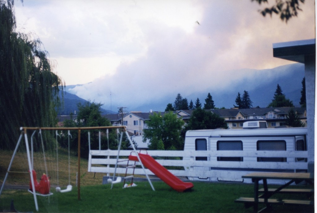 Fire burning in hills. Smokey background. Children's swing set in foreground.