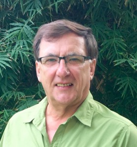 Portrait of a dark haired man with glasses smiles.