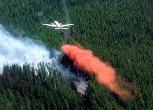 Feu et fumée dans les collines. Retardant rouge largué d'un avion.