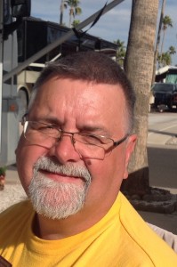 Homme avec une barbiche et lunettes sourit.