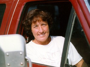Woman sits in passenger seat of a red truck.