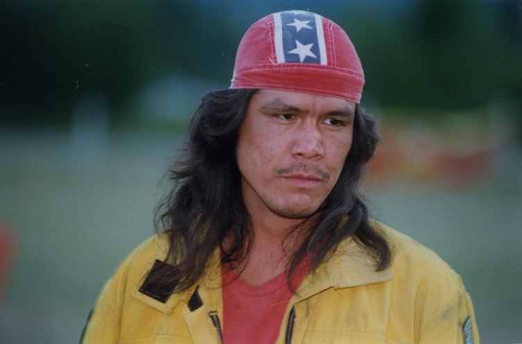 Portrait of a man in yellow coveralls with a cap on head.