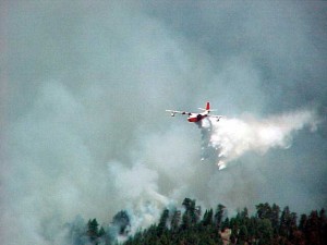 Aeorplane dropping fire retardant on a forest fire.
