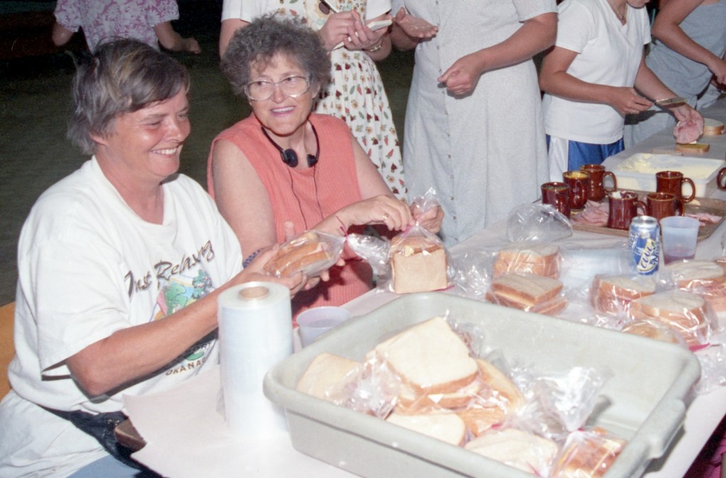 Two women chat as they make sandwiches.