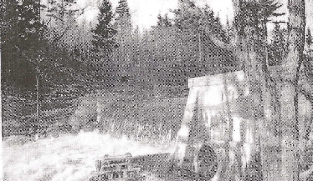 A black and white photo showing the water rushing over the Chester Electric dam on the East River. The dam, constructed of concrete has the date 1919 on it.