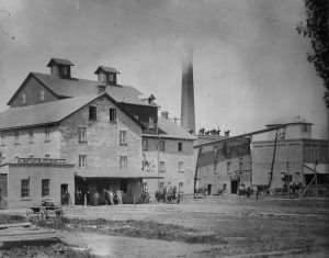 Stone mill with two brick structures to the right.