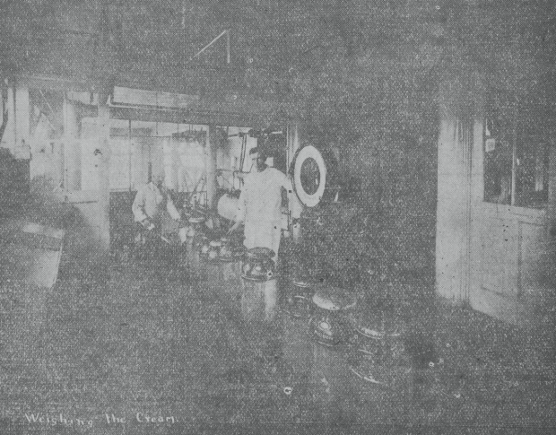 Black and white photograph of two men next to cream cans.