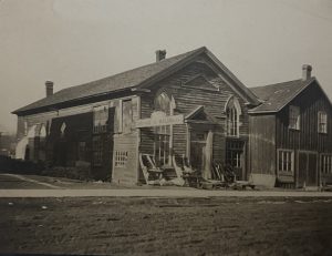 Wood frame structure with carriage parts out front.