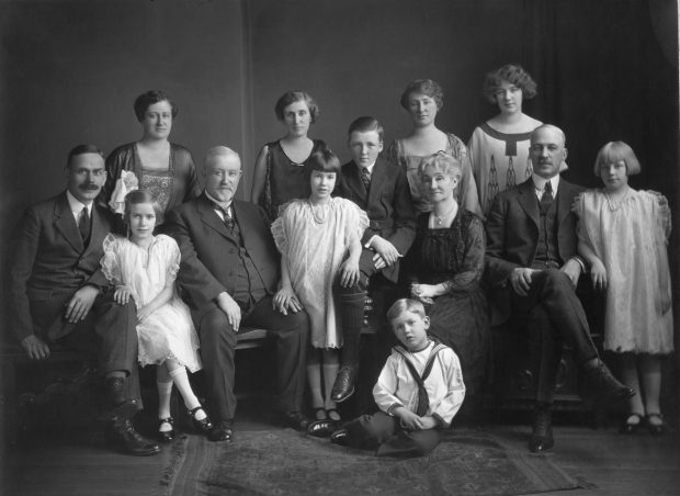 Men, women, and children dressed in dresses and black suits.