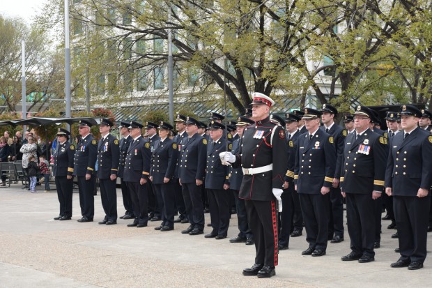 Guardsman Blaine Gray stands with ceremonial sword in front of row of uniformed firefighters at Tribute Plaza in 2015.