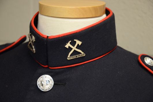 Close up of collar pins, with crossed axes and the previous spelling of 'Honor Guard'.