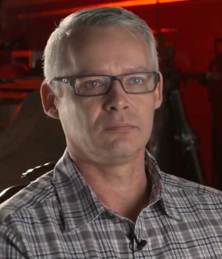 Colour head and shoulder photo of Grant Rinas wearing a plaid shirt.