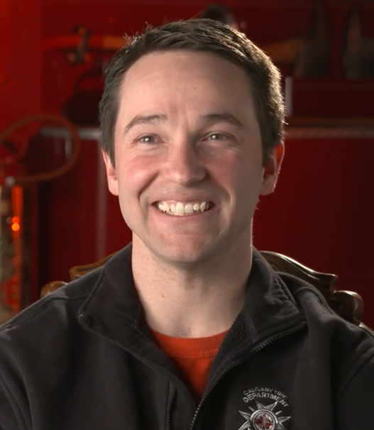 Head and shoulder colour photograph of Tobias Breuer wearing a black jacket with a Calgary Fire department logo.