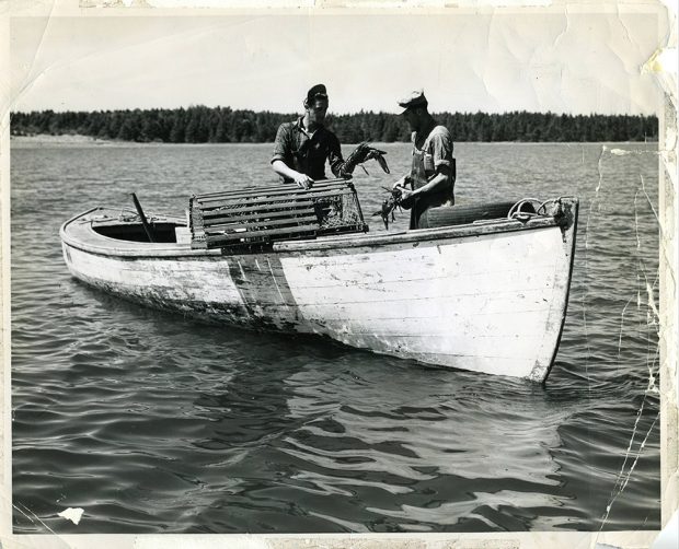 Black and white Photograph of two men on a boat with lobsters and traps
