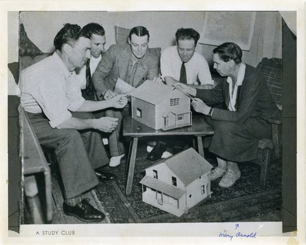 Black and white photograph of a group of men and women in a study group with model houses. Hand written at the bottom Mary Arnold