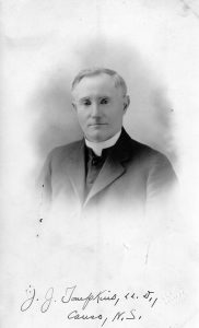 Black and white portrait photograph of Father Tompkins. written at the bottom 